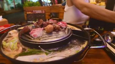 Geleneksel Tayland BBBQ bifteği (Moo Krata), karışık deniz ürünleri, ahtapot, karides, balık köftesi, erişte, mantar, lahana, mısır, sarımsak ve Tayland, Bangkok 'ta ahşap masaya soslar..