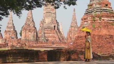 Tayland, Ayutthaya - 15 Mart 2023: Geleneksel Tayland elbiseli kadın antik Buda heykelini ziyaret ediyor. Ayutthaya tarihi parkı. UNESCO Dünya Mirası Alanı