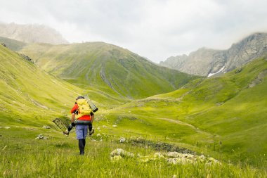 Beyaz erkek ve kadın yürüyüşçüler dağ manzarası afişinde yürüyorlar. Yazın açık havada gezen çiftlerin panoramik portresi. Baharda birlikte seyahat eden çift.