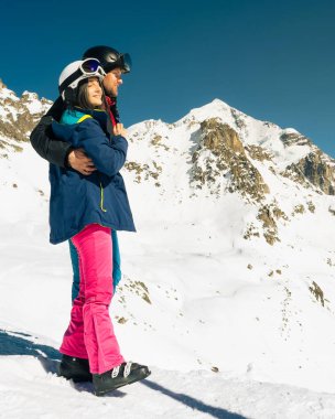 Genç beyaz çift, kışın karlı dağlara bakarken sarılıyor. Tatillerde kayak yaparak uzaklaşmak. Tetnuldi kayak merkezinin bakış açısı. Kafkas dağları yüksek irtifa azaltılıyor