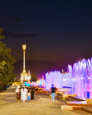 Dushanbe, Tacikistan - 15 Kasım 2023: Dushanbes merkez Dusti Meydanı 'ndaki renkli aydınlatma çeşmeleri ve altın heykel sütunları