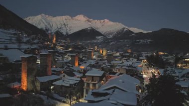 Günbatımından sonra kar, Mestia köyünü kapladı. Parlayan Svan kuleleri, geleneksel mimari ve alacakaranlık gökyüzünün altındaki dağ zirveleri. Popüler kayak tatil beldesi Avrupa