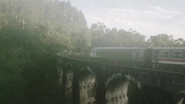 Yükselen hava manzaralı yolcu treni bulutlu sabahın erken saatlerinde yemyeşil sularla çevrili Ella, Sri Lanka yakınlarındaki ikonik dokuz kemer köprüsünü geçer.
