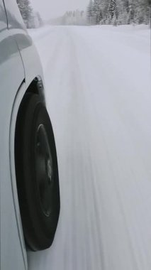 Bakış açısına göre ön tekerlekler buzlu karla kaplı yolda kuzeye doğru ilerliyor. Soğuk hava koşulları, yol tutuşu ve mevsimsel seyahat koşullarını gösteriyor.