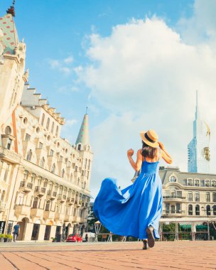 Gürcistan 'ın başkenti Batumi' de Avrupa Meydanı 'nı gezen mavi elbiseli ve yaz şapkalı genç bir turist. Karadeniz tatil beldesi Batumi 'de canlı turizm ve kültür