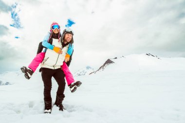 Heyecanlı genç ve neşeli çiftimiz kış tatillerini dışarıda, karlı arazide birlikte geçiriyorlar. Dağlarda mutlu romantik bir an. Kış tatilleri açık havada, harikalar diyarında.