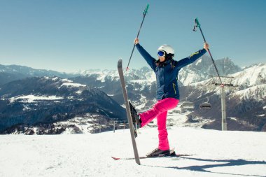 Kayak merkezinde kayakla poz veren mutlu kadın kayakçı Avrupa dağlarında kış sporu mavi gökyüzü kopyalama alanı