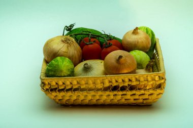 Salatalıklar, domatesler, hasır sepette soğanlar beyaz arka planda. Organik sebzeler diyet için iyidir, çünkü birçok vitamin ve mikroelement içerir. Manzara yönelimli resmi kapat.