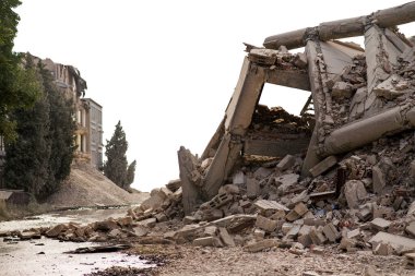 Çökmüş beton endüstriyel bina beyaza izole edilmiş. Enkaz, toz ve hasarlı evlerle dolu felaket sahnesi.