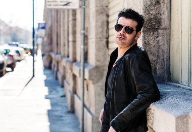 Güneş gözlüğü ve deri ceket giyiyor şehirde yakışıklı adam