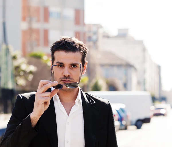 Bonito retrato de homem tirando óculos de sol na cidade — Fotografia de Stock