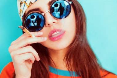 Hippy girl smoking and wearing sunglasses clipart