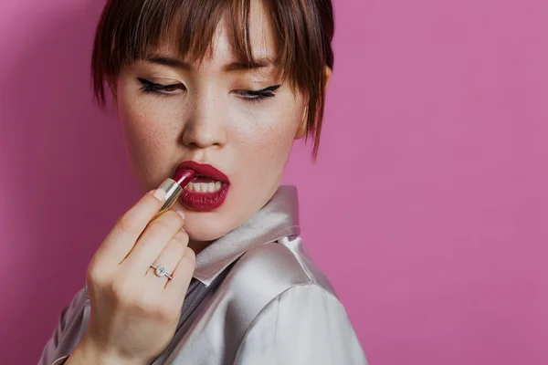 Mädchen-Schönheitsporträt legt roten Lippenstift an, während sie nach unten schaut — Stockfoto