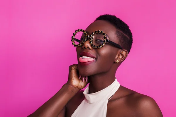 Menina africana engraçada com a língua presa usando óculos estranhos — Fotografia de Stock