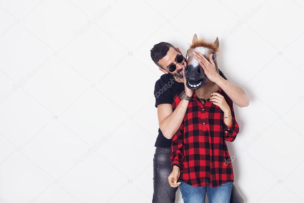Man playing hide-and-seek with his horse head girlfriend