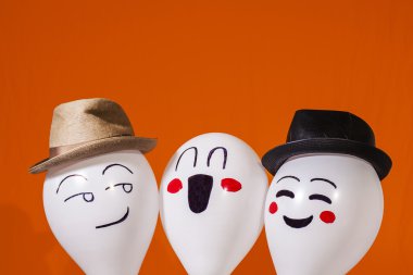 Turuncu zemin üzerine şapka giymiş balon karakterler