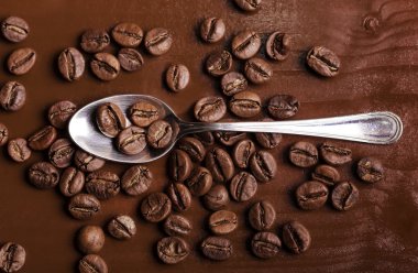 Çay kaşığı ve ahşap üzerine kahve çekirdekleri