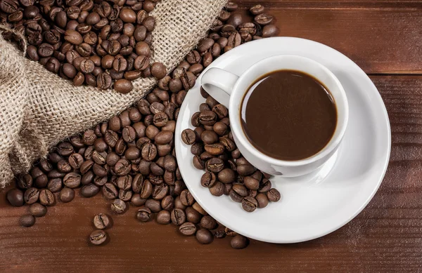 Koffiekopje en jute zak vol met koffie bonen — Stockfoto