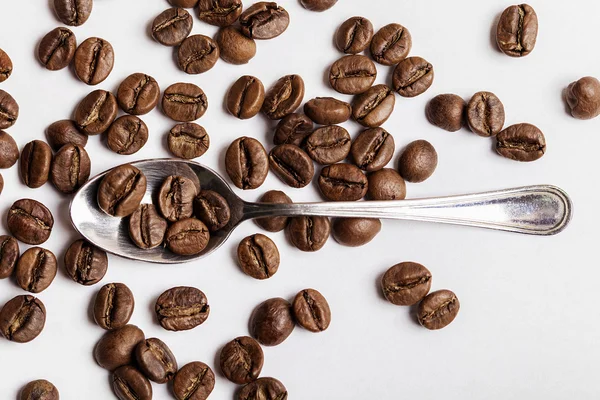 Cucharadita y granos de café en blanco — Foto de Stock