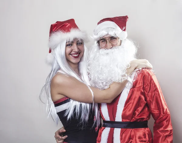 Santa Claus and girl wearing Christmas hat smiling — Stock Photo, Image