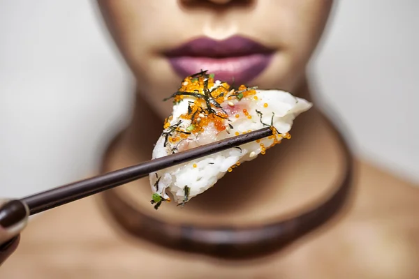 Beautiful model holding sushi with chopsticks — Stock Photo, Image