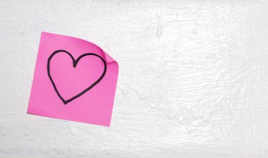Pembe post it çizilmiş kalp duvar üzerinde
