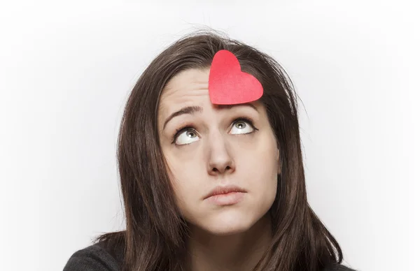 Smutná dívka na papírové srdce při pohledu na čelo — Stock fotografie
