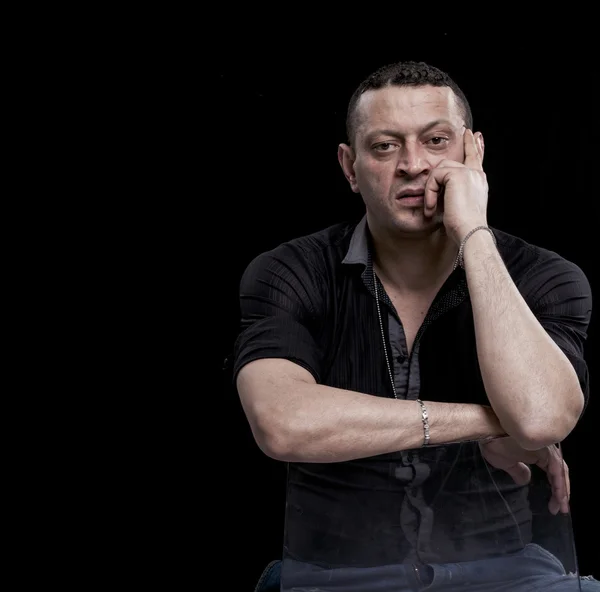 Frowning and thoughtful man sitting on a chair — Stock Photo, Image