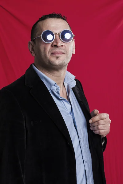 Man stående bär solglasögon på röd bakgrund — Stockfoto
