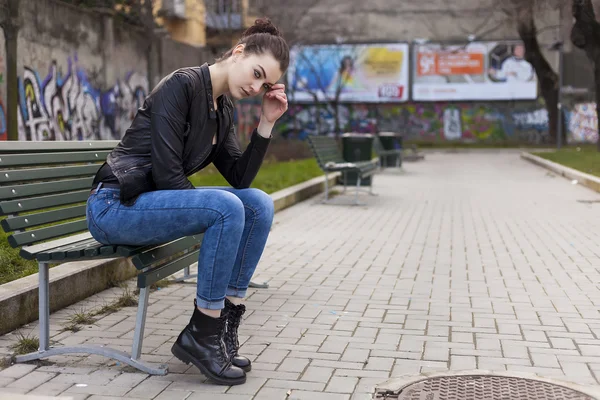 Krásná dívka sedící na lavičce a hledá — Stock fotografie