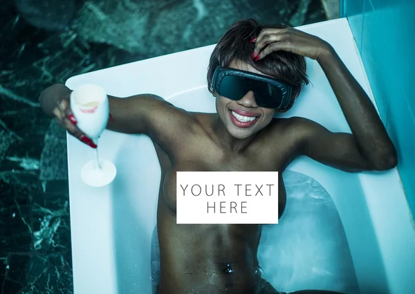 Naked african model in the bathtub with a drink card — Stock Photo, Image