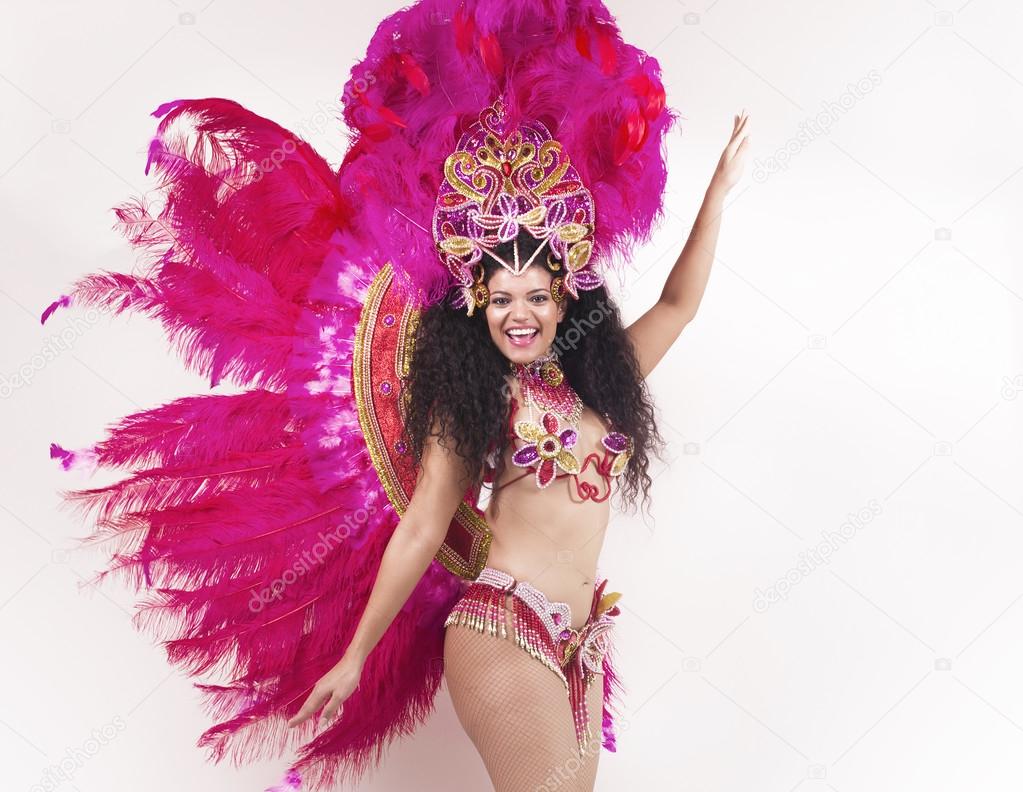 Cheerful samba dancer wearing traditional pink costume and posin
