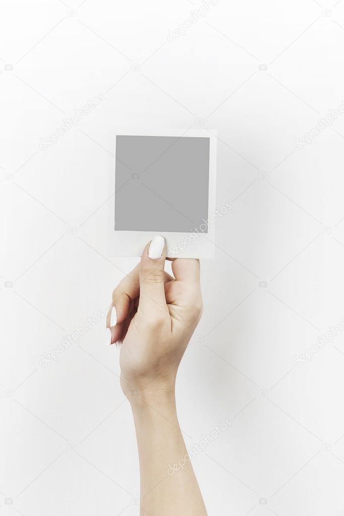 Female hand holding polaroid with grey blank space