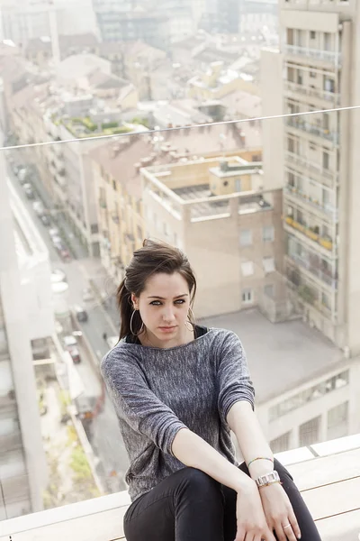 Mooi meisje zit en op zoek en wazig stadsgezicht — Stockfoto