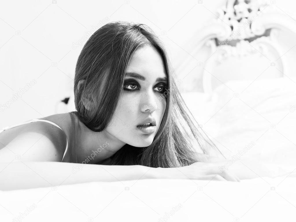 girl lying on bed and looking black and white Stock Photo by
