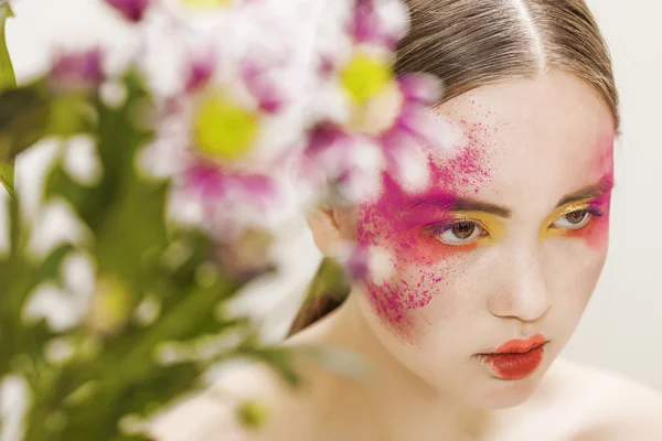 Underbara flicka porträtt klädd i färgglada makeup och blommor — Stockfoto