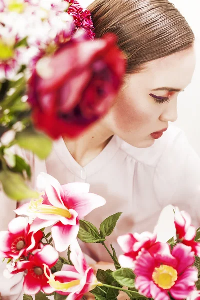 Pretty woman looking aside and flowers — Stock Photo, Image