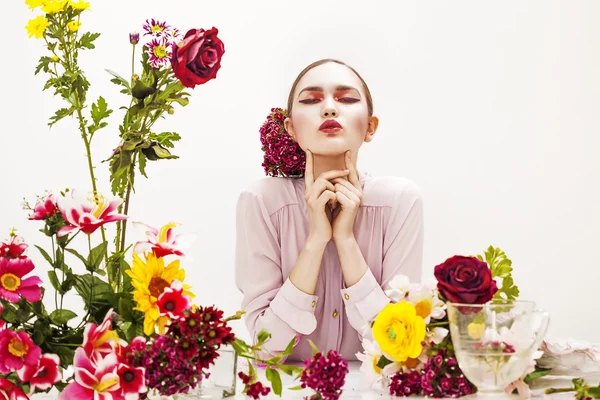 Vacker kvinna porträtt sitter vid bordet med blommor — Stockfoto