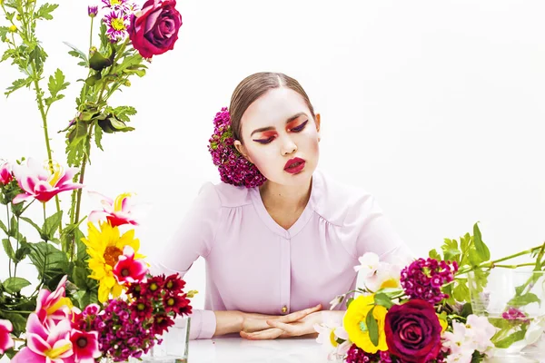 Eftertänksam kvinna porträtt sitter vid bordet med blommor — Stockfoto