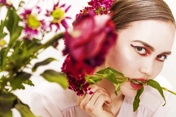 Donna ritratto di bellezza mordere ramo di fiore e fiori sfocati — Foto Stock