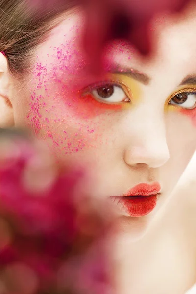 Chica primer plano retrato de belleza con flores rojas borrosas — Foto de Stock