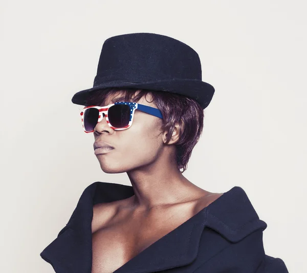 Schönes afrikanisches Model mit Mantel, Hut und amerikanischer Sonnenbrille — Stockfoto