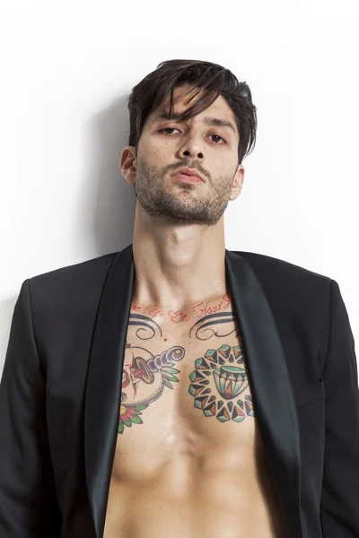 Tatuado homem vestindo casaco preto e olhando para a câmera — Fotografia de Stock