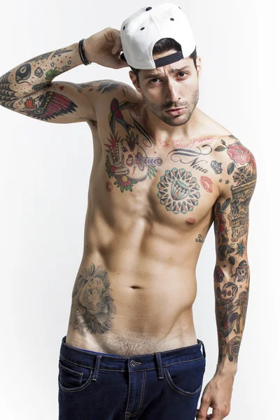 Bonito e sexy tatuado homem vestindo boné de beisebol e posando — Fotografia de Stock