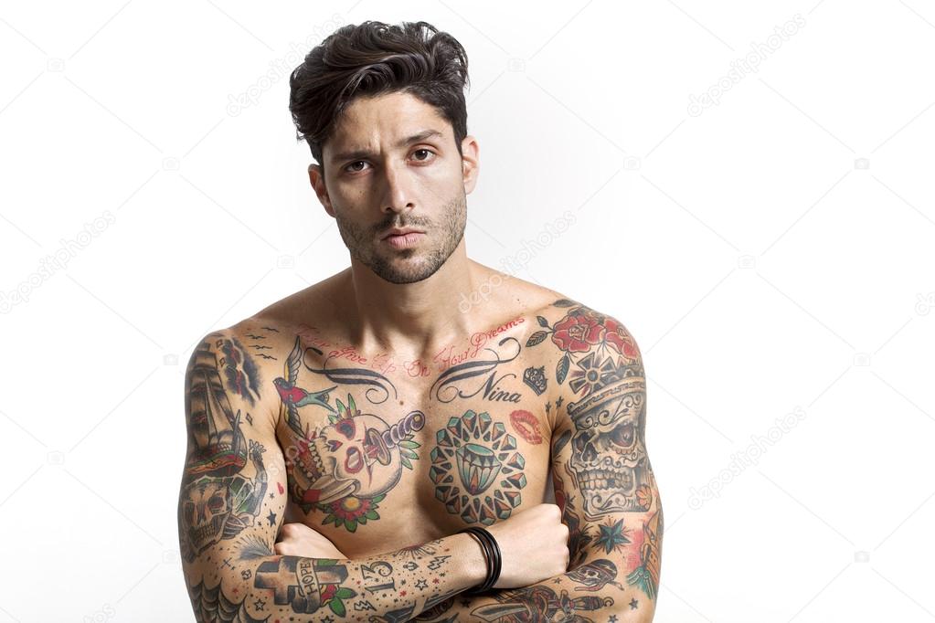 Sexy tattooed man portrait with crossed arms looking at camera