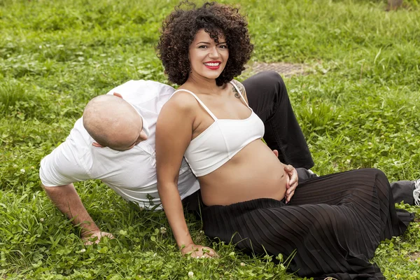 Pareja embarazada retrato sentado en la hierba — Foto de Stock