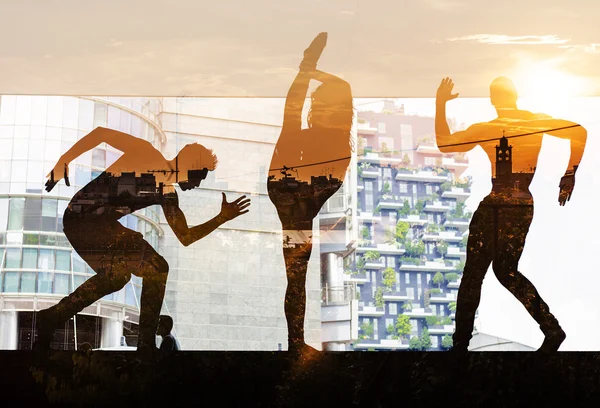 Double exposure of dancers silhouettes and city sunset — Stock Photo, Image