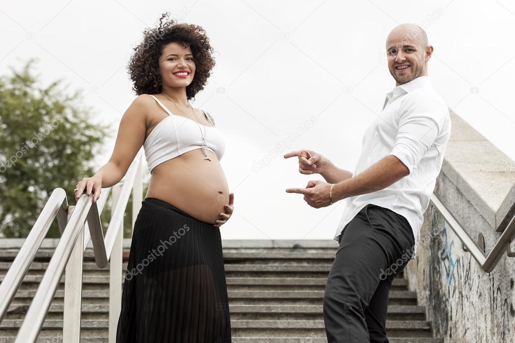 Beautiful pregnant couple portrait on the stairs in the city