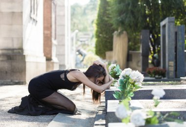 Keder bir mezarı önünde tutulmuş kadın portresi