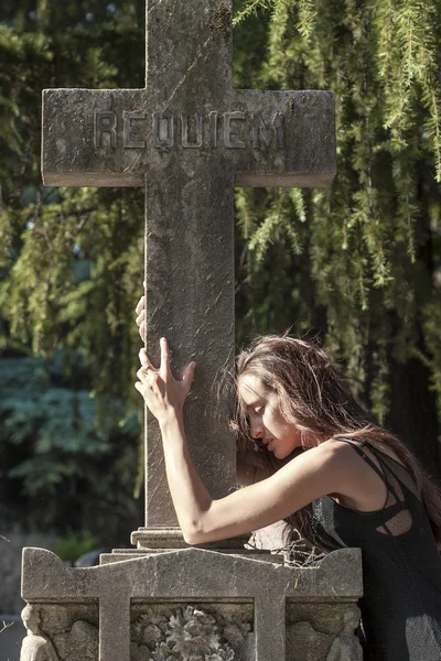 Retrato de mujer en pena que encierra una cruz grave —  Fotos de Stock